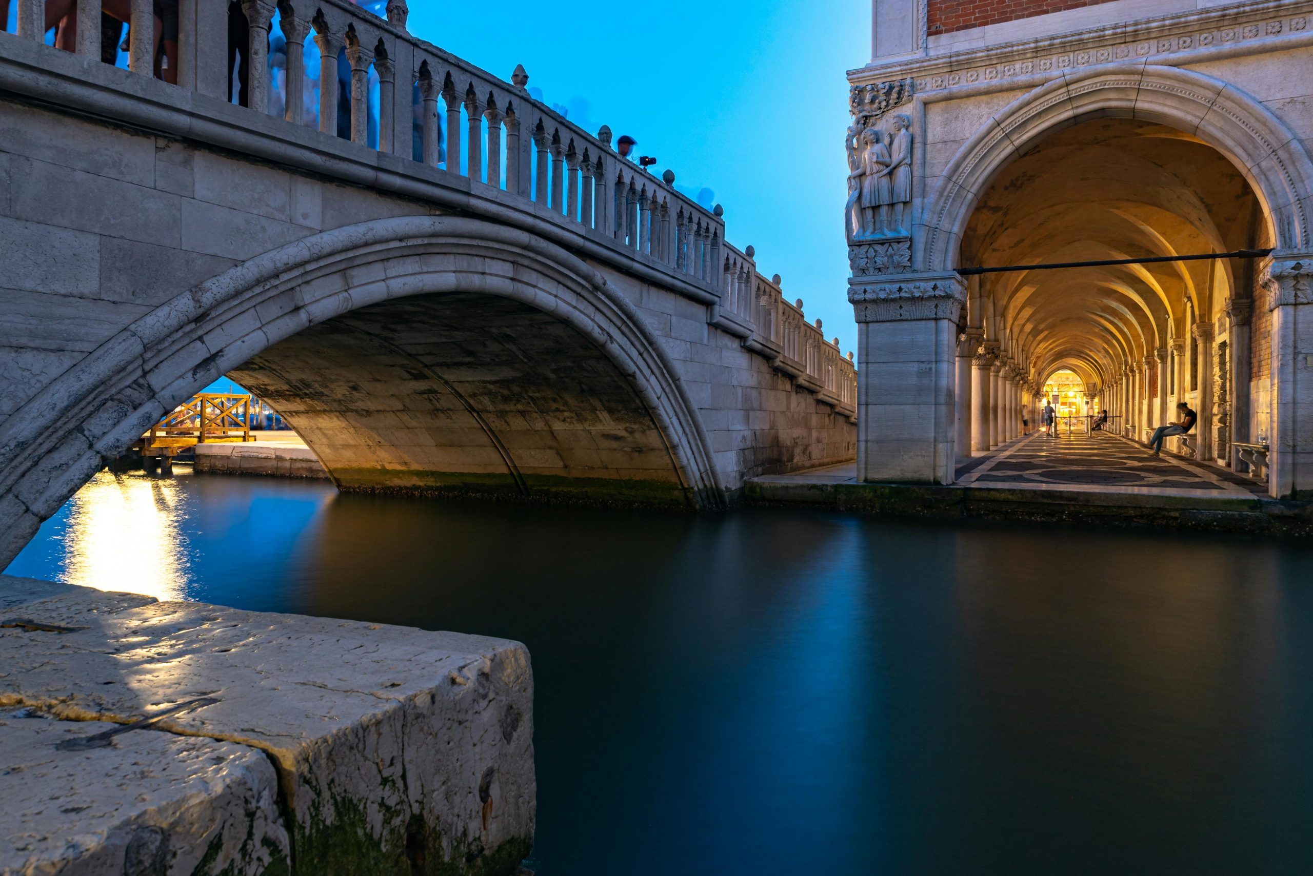 Scenic view of a historic bridge and arch in Venice at twilight, capturing the charm of Italian architecture.