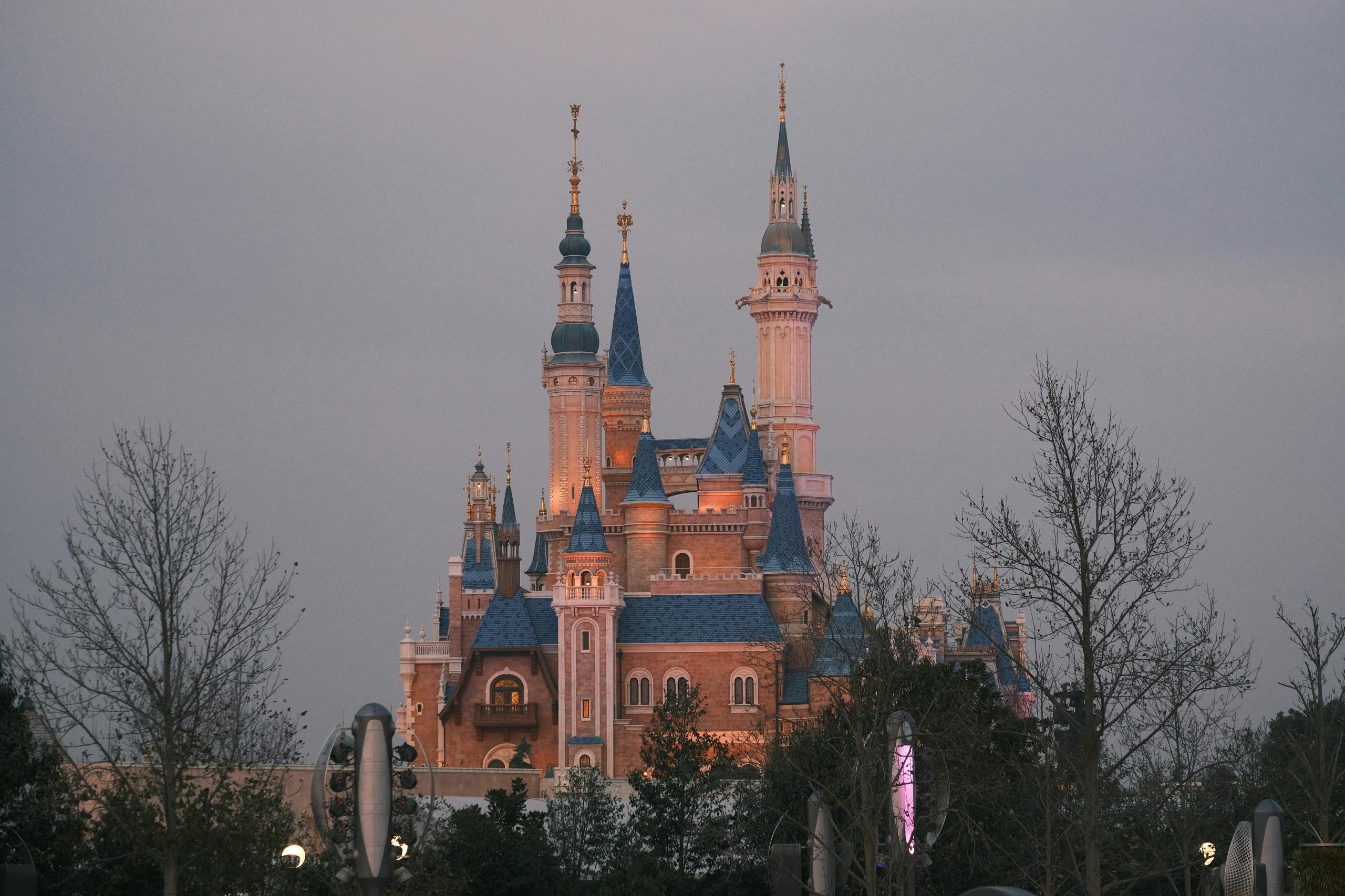 Twilight view of the enchanting castle at Shanghai Disney Resort, surrounded by trees.