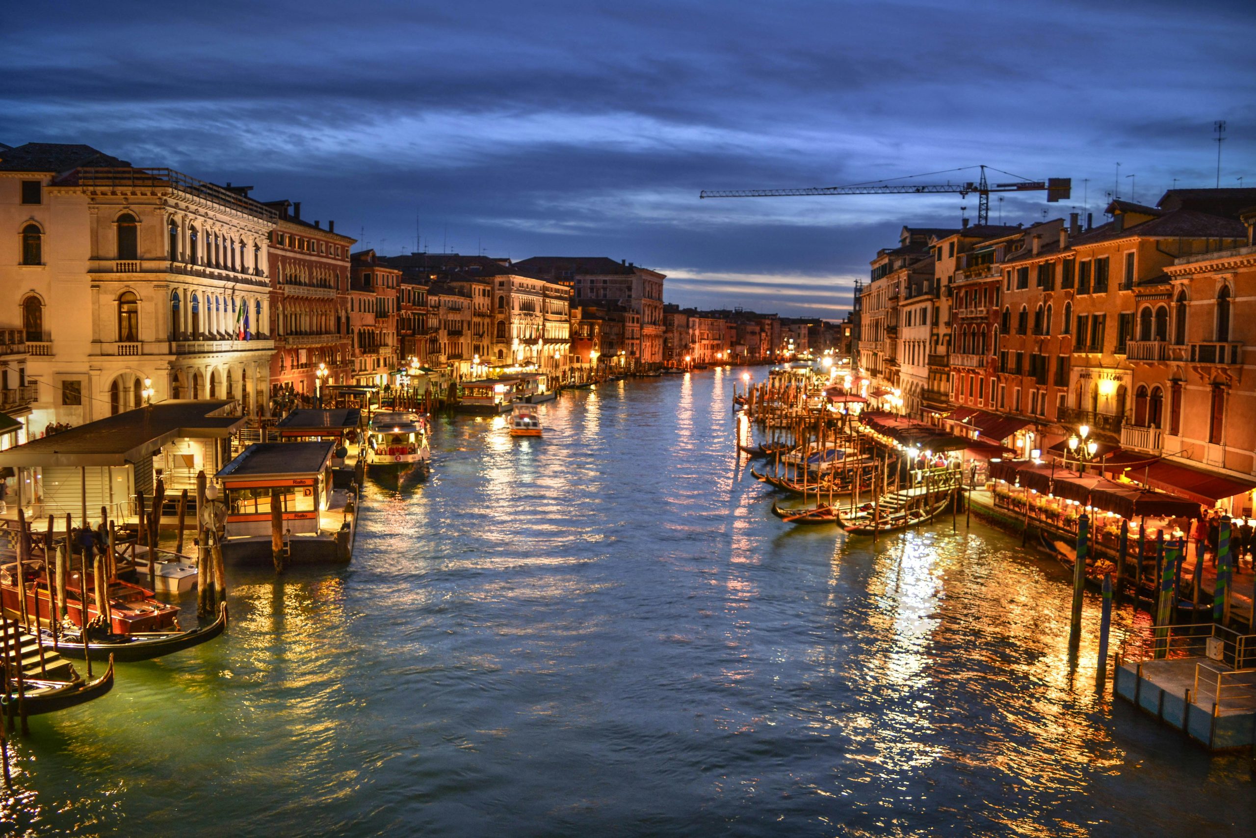 Stunning evening shot of Venice's Grand Canal with illuminated waterfront buildings and docked boats.