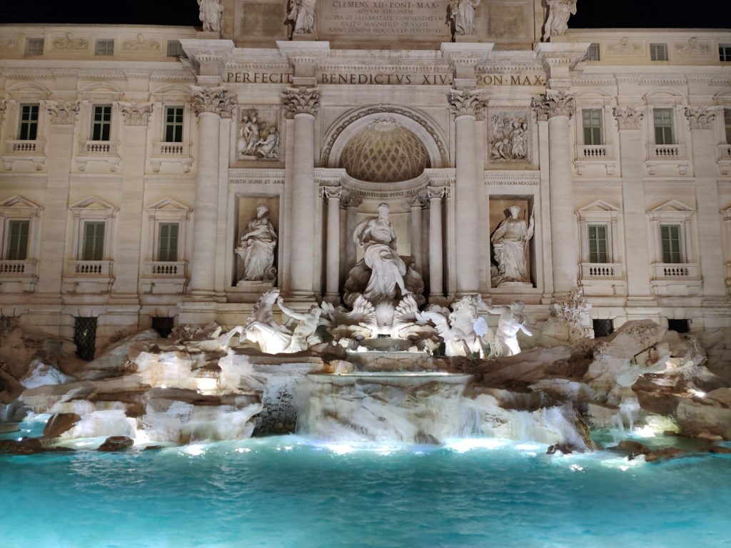 Fontana di Trevi monedas significado — turistas lanzando monedas al agua en Romaome's iconic monument, beautifully illuminated.