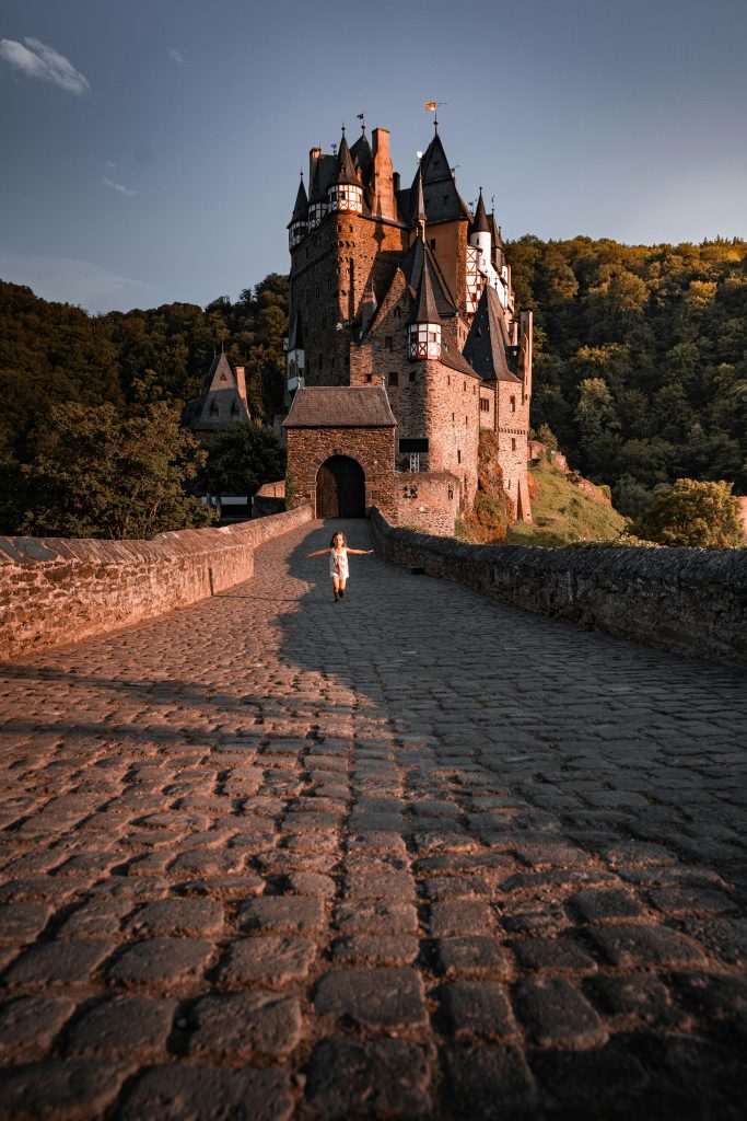 Eltz Castle in Germany, captured at sunset, surrounded by lush forest and historic architecture.